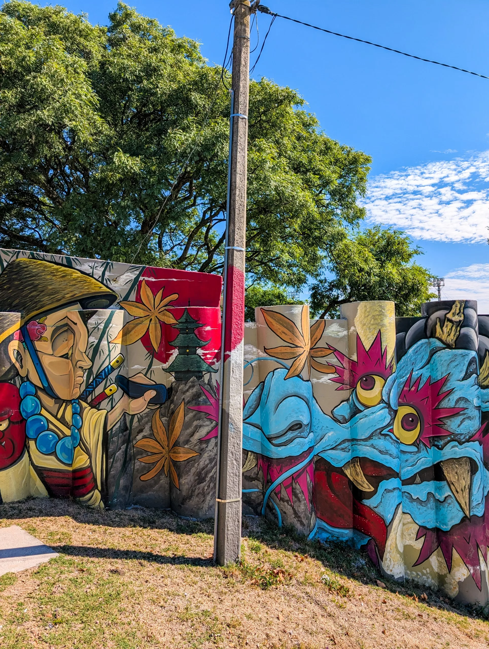 Une fresque murale réalisée à Colonia del Sacramento sur un mur incurvé représente une personne coiffée d'un chapeau et portant un collier de perles, tendant la main vers un dragon bleu.
