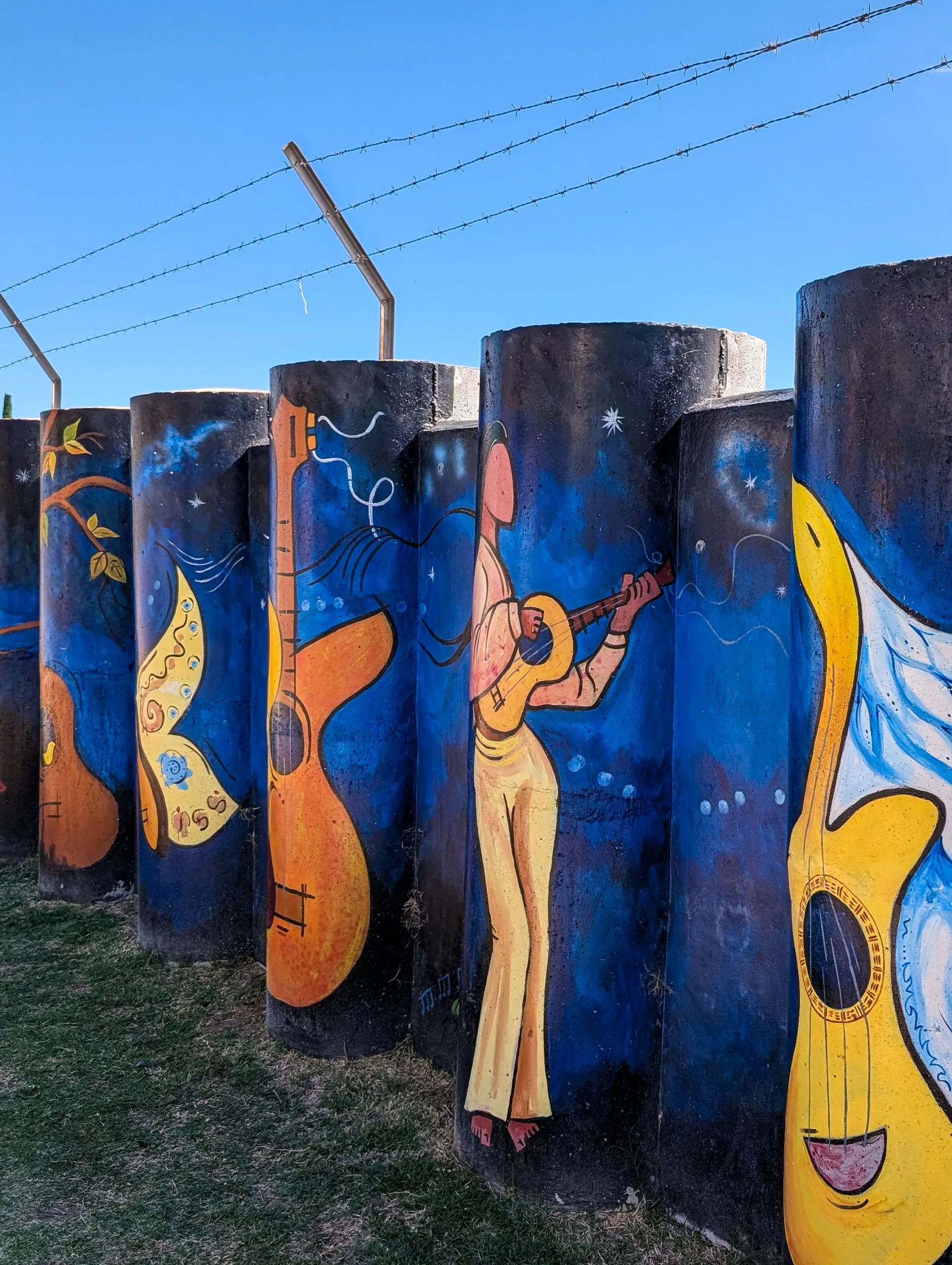 Une fresque murale prise de côté, bleue avec des personnages jouant de la musique et des instruments dans des formes arrondies.