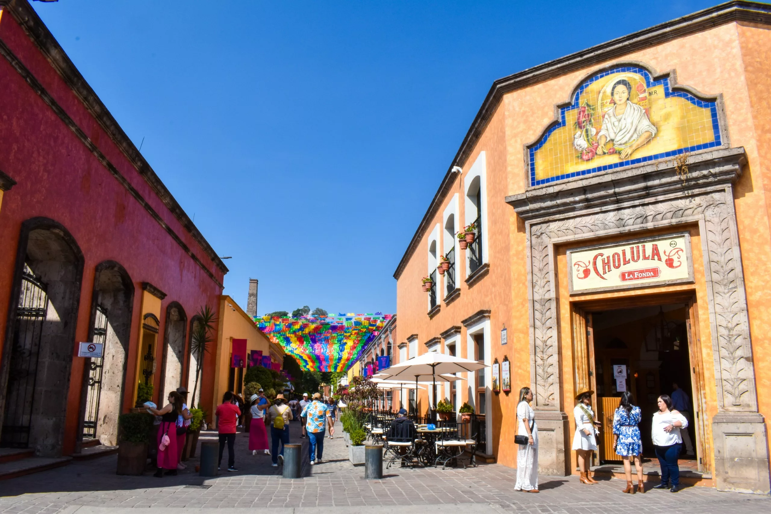 Les gens se promènent dans une rue piétonne animée de Tequila, au Mexique, bordée de terrasses et ornée de banderoles en « papel picado »