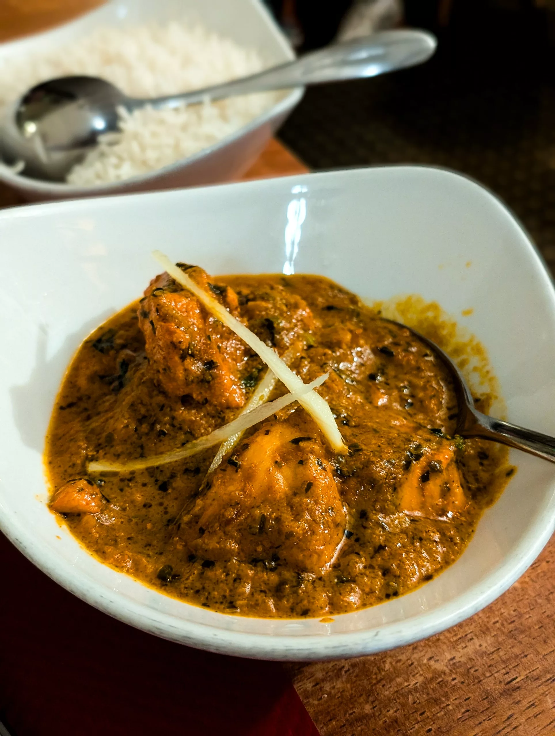 Un bol de poulet au curry garni de lamelles de gingembre et accompagné de riz